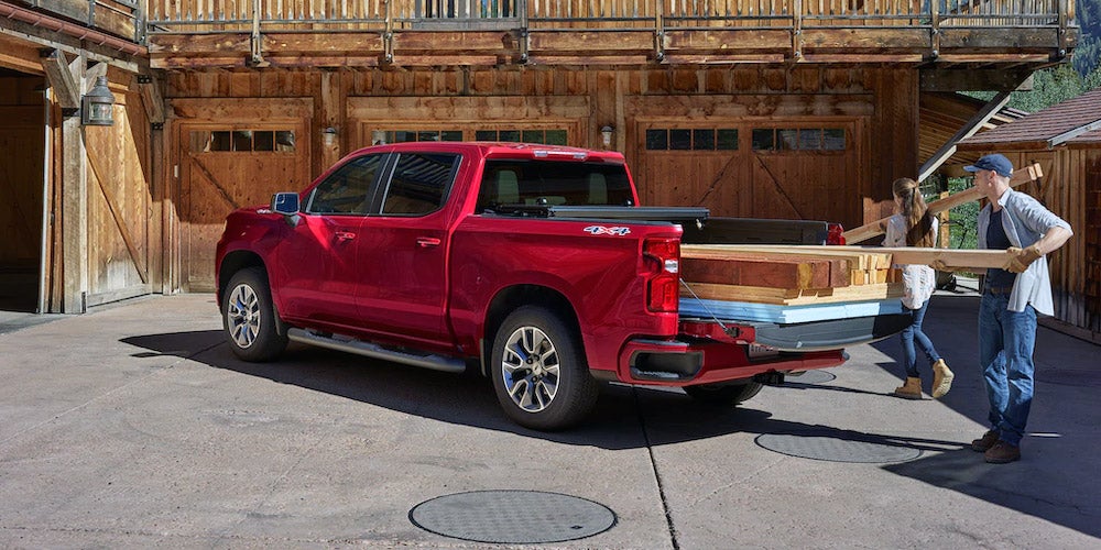 People loading lumber into the bed of a Silverado truck